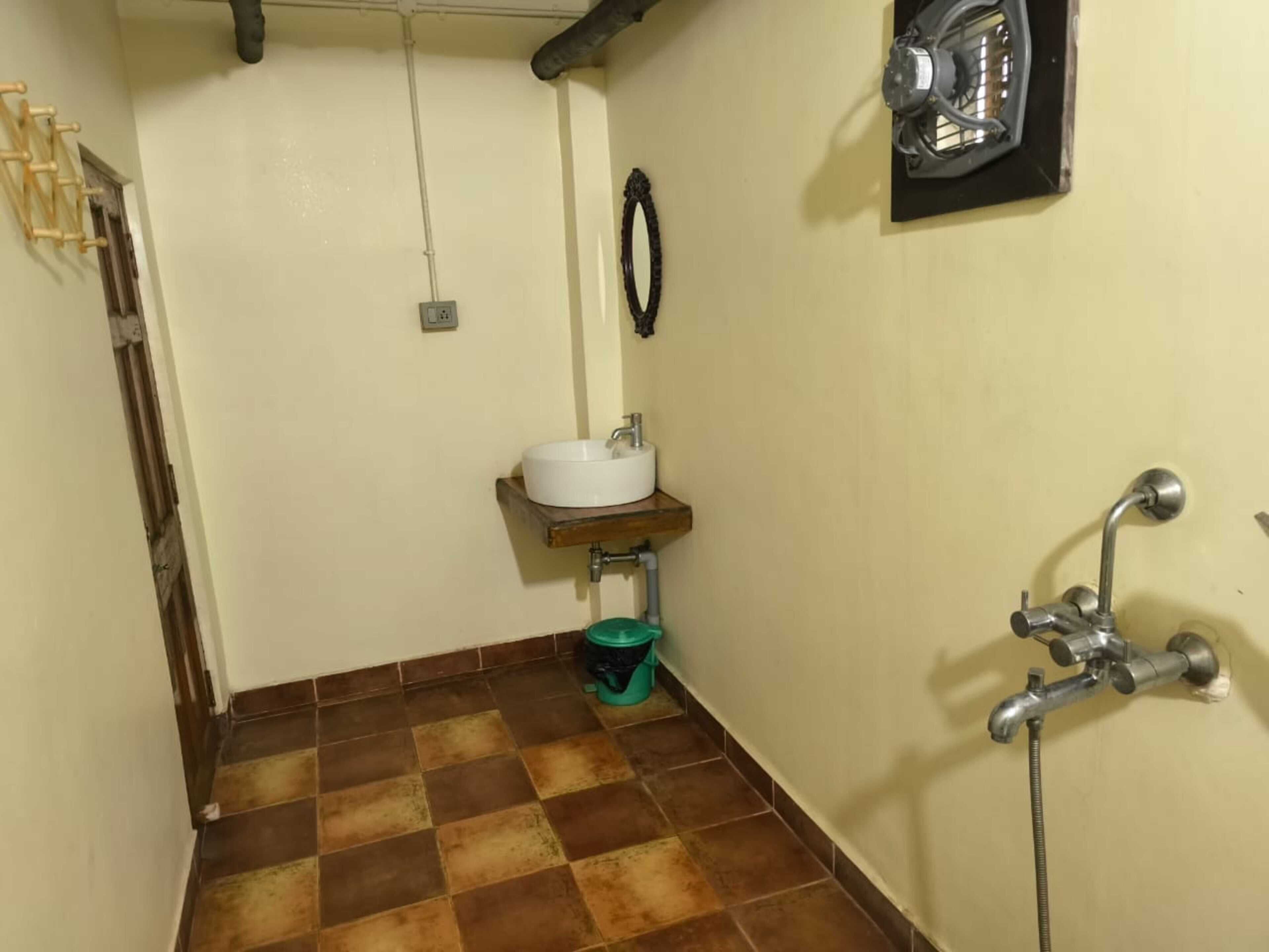 A small bathroom with a white sink, a green trash bin, a shower, and a towel rack.