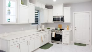 A modern kitchen with white cabinets, a stainless steel oven, a microwave, and a sink. - Vista Verde Suite In Alamo Tx (Alamo)