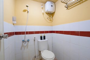 A small bathroom with a toilet, a shower, and a hand dryer. - Apartemen Mutiara Bekasi By Abdihome (Bekasi)