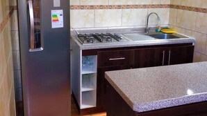 Egy konyha, amelyben rozsdamentes acél hűtőszekrény, mikrohullámú sütő, gáztűzhely és mosogató található.