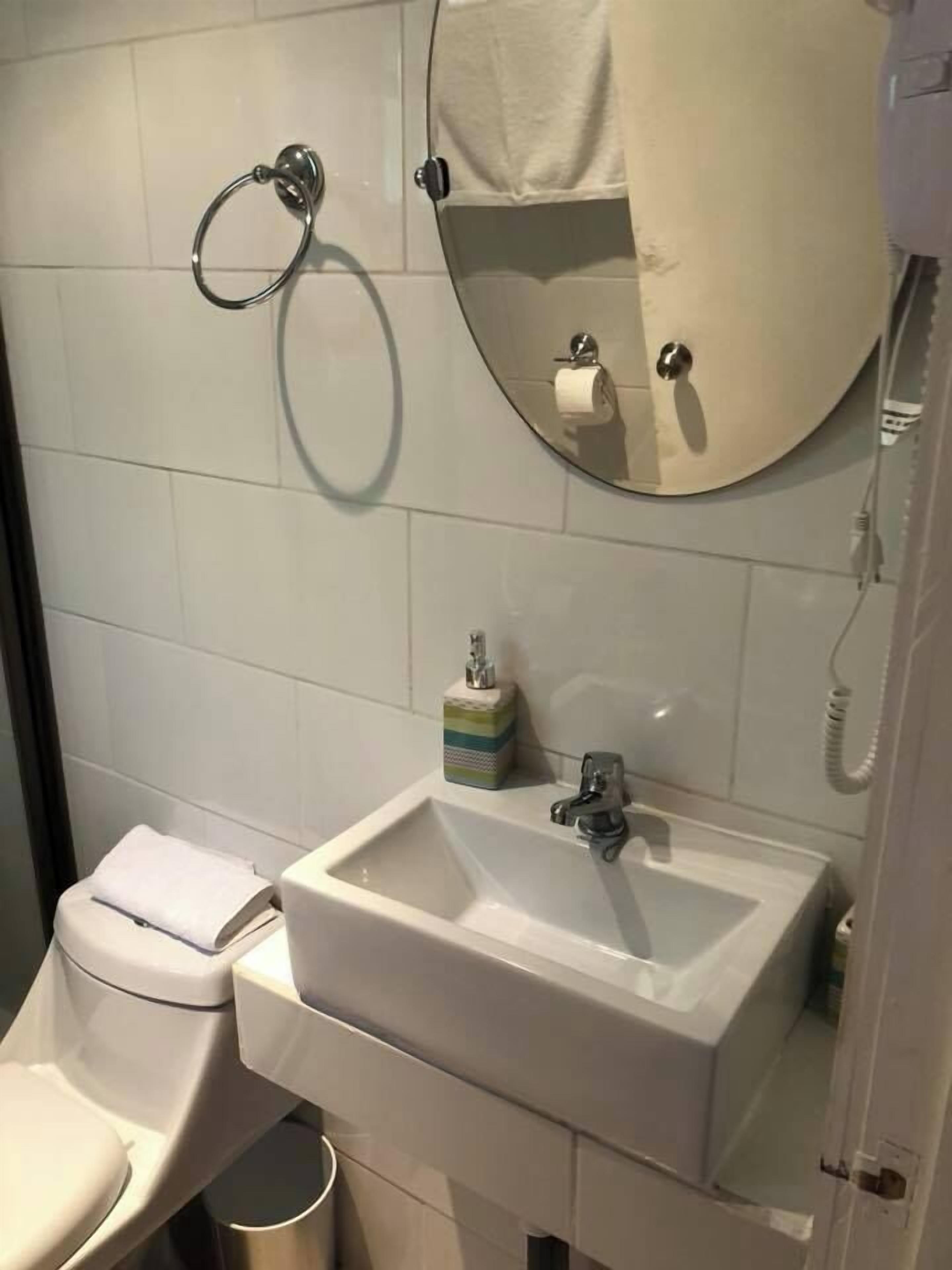 A bathroom with a toilet, sink, and mirror.
