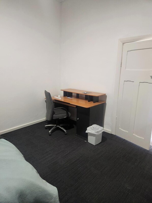 Un petit bureau comprenant un bureau, une chaise et une poubelle.