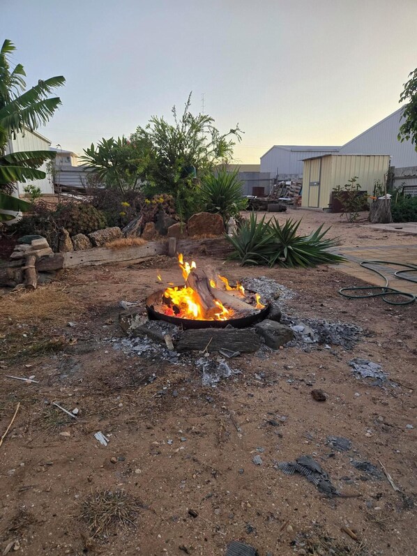 A fire pit in a yard with surrounding vegetation and a building in the background. - Port Neill SA Stone Cottage Close to everything in Pt Neill Sleeps 6 (Port Neill)