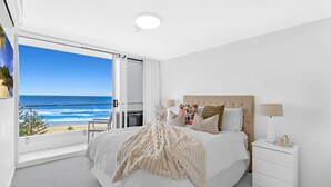 Ein Schlafzimmer mit einem großen Bett, einem Nachttisch und Blick auf den Ozean.