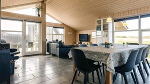 Un vaste espace de vie comprenant un grand canapé, une table à manger avec des chaises et un téléviseur.