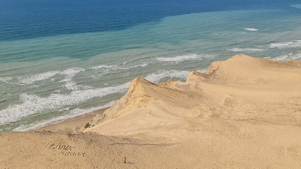 Un paysage côtier avec une plage de sable et l’océan.
