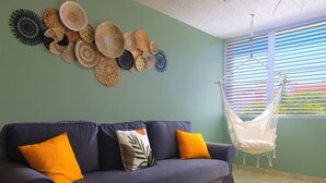 Ein Wohnzimmer mit einer Couch, Kissen, einem Hängesessel und einer Wand, die mit gewebten Körben dekoriert ist.
