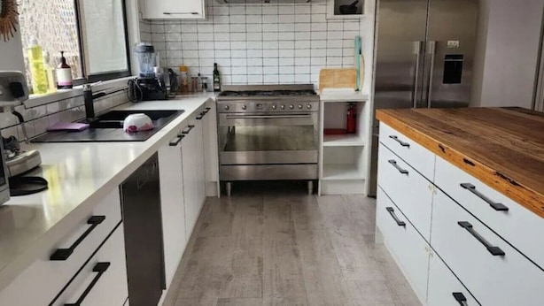 A modern kitchen with white cabinets, a stainless steel stove, and a wooden countertop. - Family beach house among the gum trees (Ocean Grove)