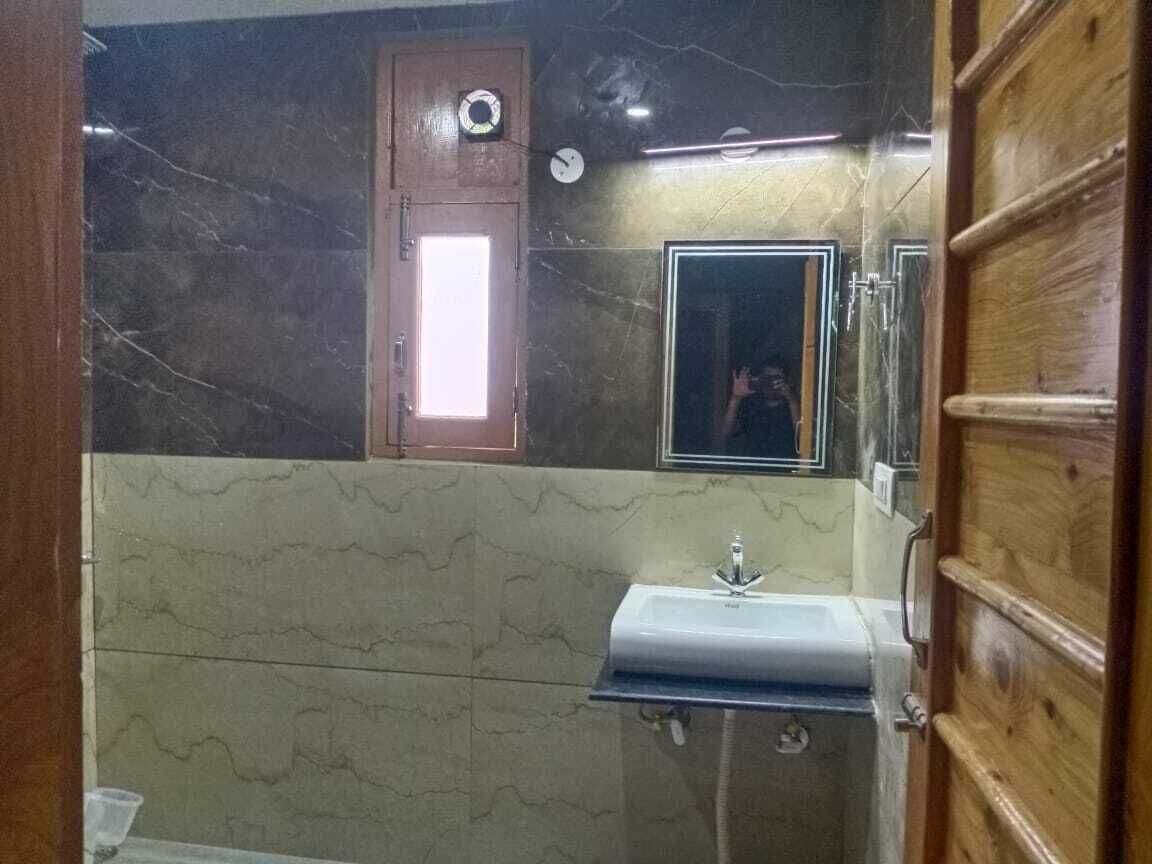 A bathroom with a marble wall, a wooden door, a sink, and a mirror.