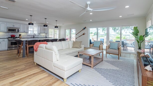 A spacious living area with a white sofa, wooden coffee table, and a dining area with a red chair.