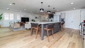 A spacious kitchen with a central island, wooden flooring, and pendant lighting.