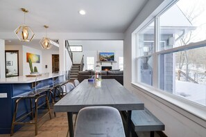 Cozinha moderna com uma mesa de jantar comprida, área de bar e uma janela grande com vista para o exterior.