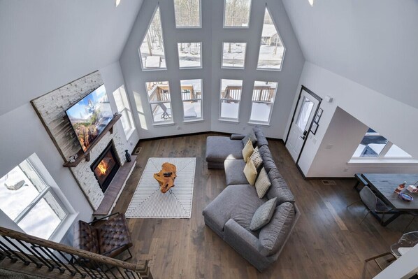 Uma sala de estar ampla em estilo loft, com lareira, janelas grandes e um espaço aconchegante para sentar.