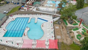 Una grande piscina con diverse corsie, circondata da lettini e ombrelloni.