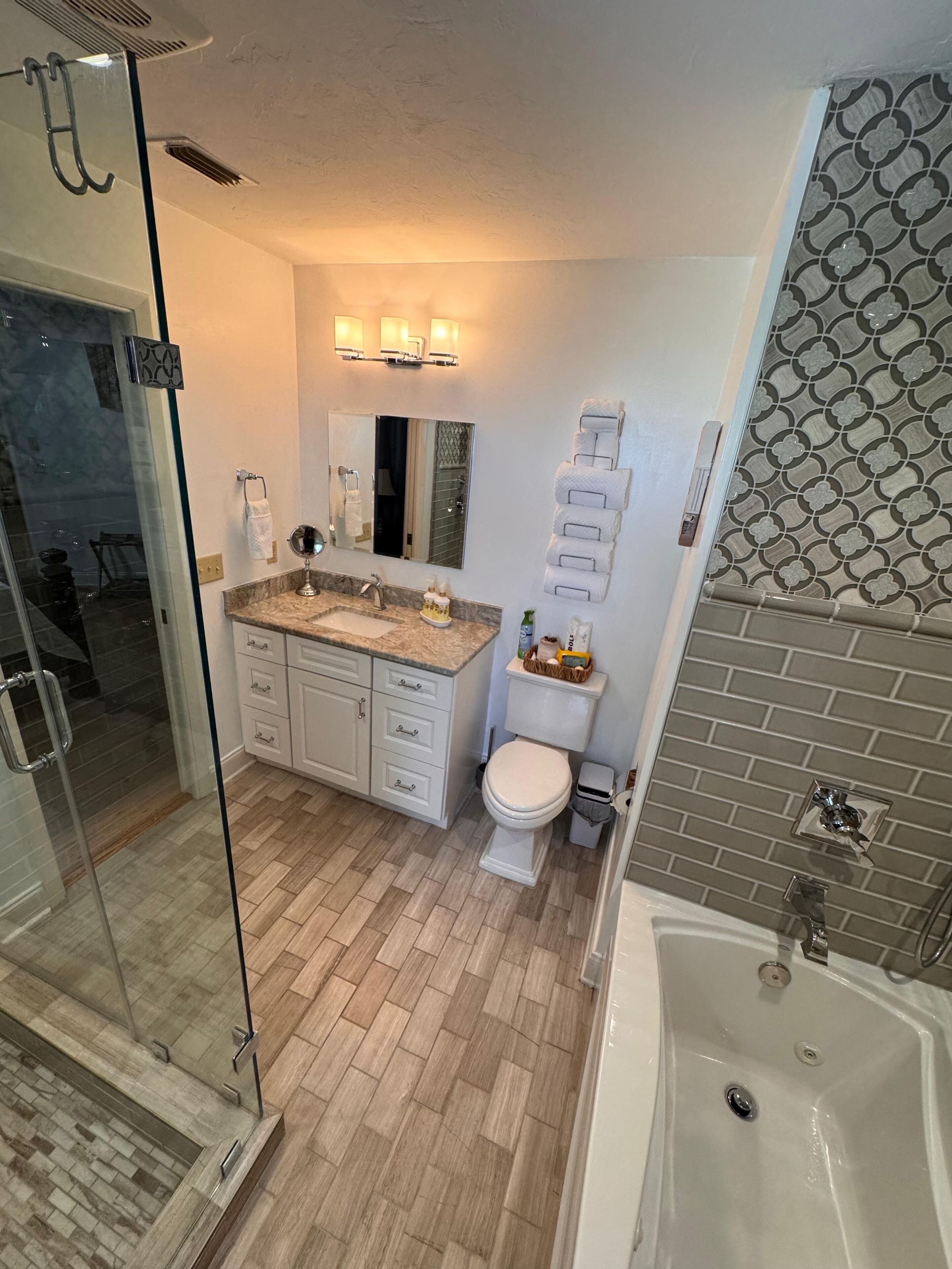 Une salle de bain moderne avec une douche à parois de verre, un lavabo sur un plan de toilette en marbre, des toilettes et une baignoire.