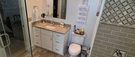 Une salle de bain moderne avec une douche à parois de verre, un lavabo sur un plan de toilette en marbre, des toilettes et une baignoire.