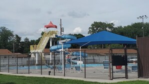 Een waterpark met een waterglijbaan, een overdekt zitgedeelte en een omheind zwembad.