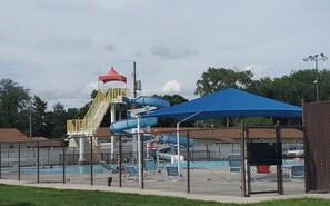 Ein Wasserpark mit Wasserrutsche, überdachtem Sitzbereich und einem umzäunten Pool.