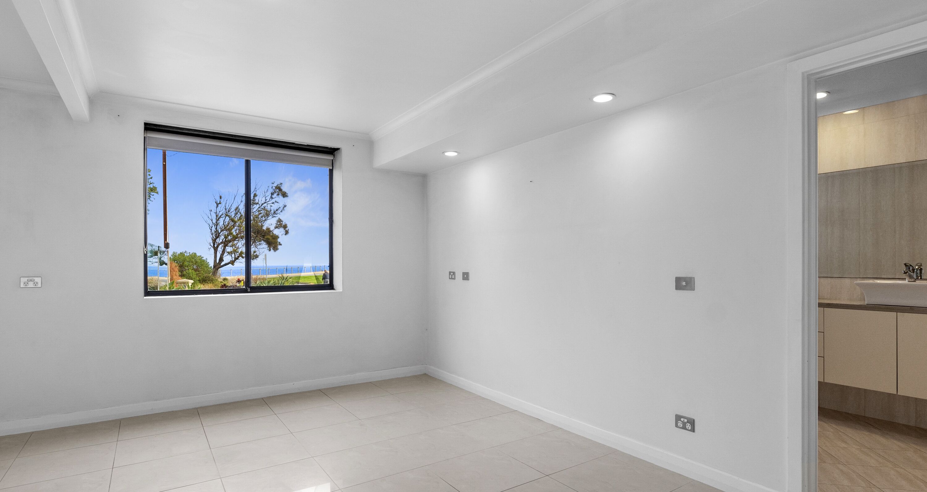 Una habitación con un ventanal grande, luces empotradas en el techo y vistas al exterior.
