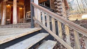 Una cabaña rústica de madera con un porche y una escalera que lleva a la entrada.