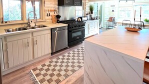 Una cocina moderna con vigas de madera, una isla grande y vistas al exterior.