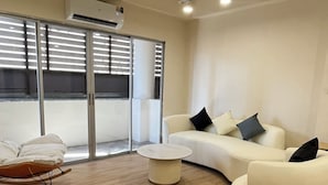 Un área de descanso moderna con un sofá blanco, una mesa de centro redonda y un sillón mecededor.