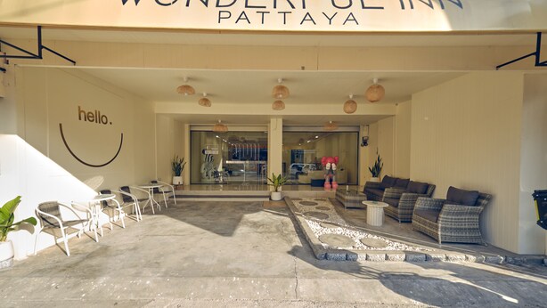 Entrada de un hotel con un cartel que dice 'hello', asientos exteriores y un cartel que dice 'Wonderful Inn Pattaya'.