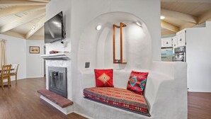 A cozy living room with a fireplace, a sofa with patterned cushions, and a television mounted on the wall.