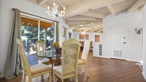 A dining area with a glass table, wicker chairs, and a chandelier.
