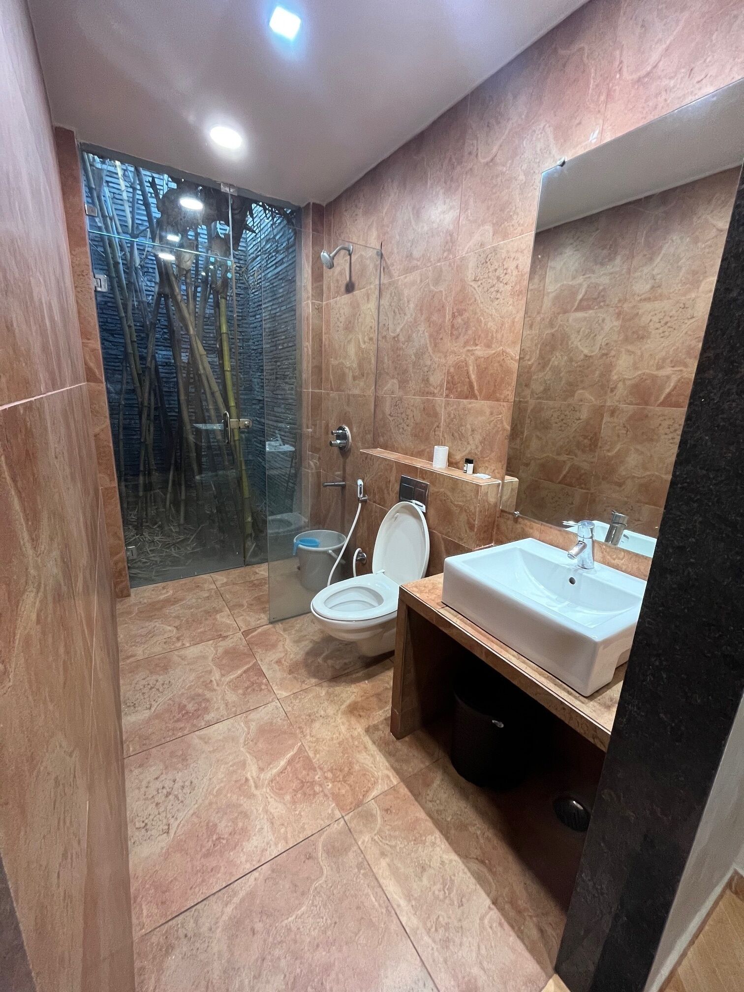 Casa de banho moderna com cabine de duche em vidro, sanita e lavatório com espelho.