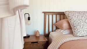 Ein Schlafzimmer mit einem Bett, einem Nachttisch, einer Lampe und einem gerahmten Bild an der Wand.