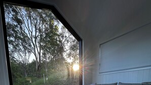 Ein gemütliches Wohnzimmer mit großem Fenster, einem runden Couchtisch und einem grauen Sofa mit Kissen.
