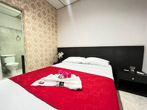 A hotel room with a bed, a nightstand, a bathroom with a toilet, and a shower area. - Casa Dorada Hotel Boutique  (Neiva)