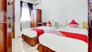 Ein Hotelzimmer mit zwei Betten, einem Kleiderschrank, einem Schreibtisch und einem Stuhl.