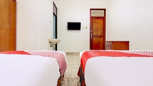 Ein Hotelzimmer mit zwei Betten, einem Fernseher, einem Holzschrank und einem Badezimmer mit Waschbecken.
