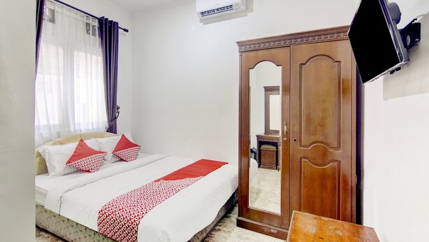 Une chambre à coucher comprenant un lit, une armoire, un téléviseur et un appareil de climatisation.