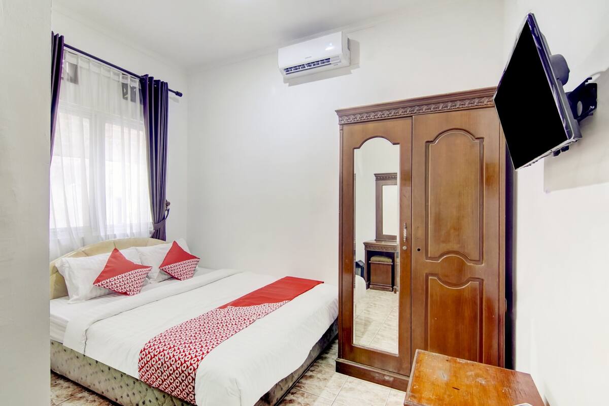 Een slaapkamer met een bed, een kledingkast, een televisie en een airconditioning.