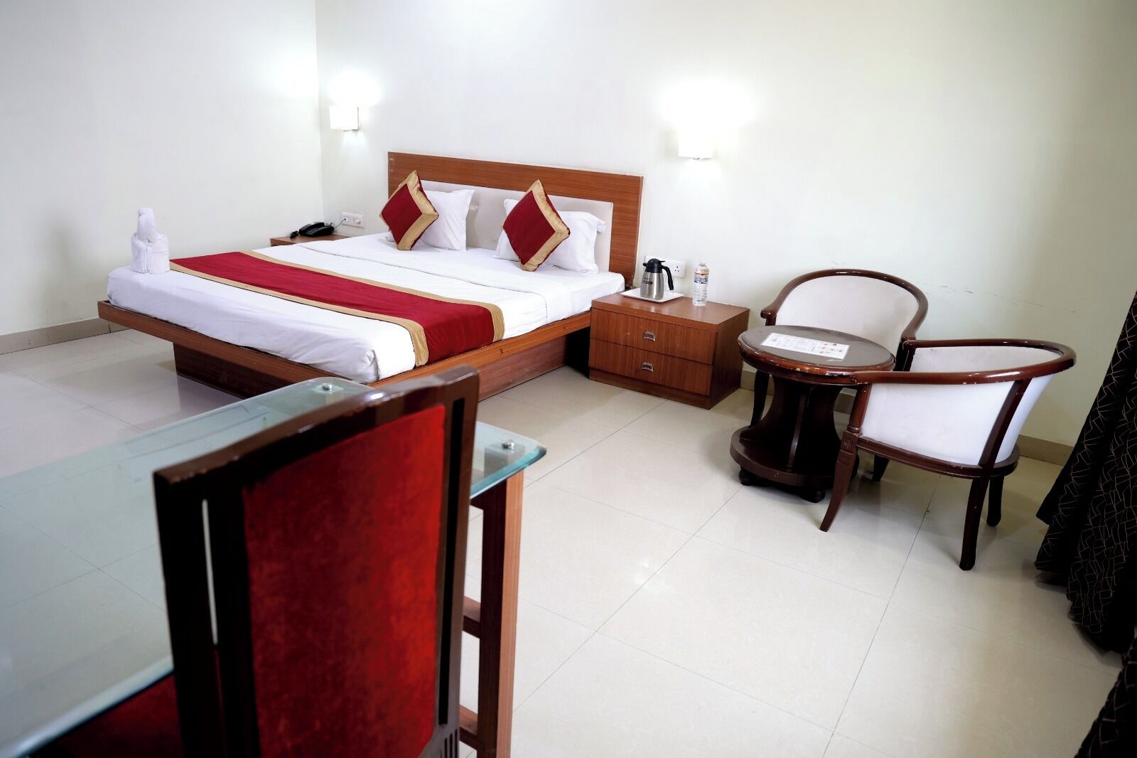 A hotel room with a bed, bedside table, chair, and a small table with a chair.