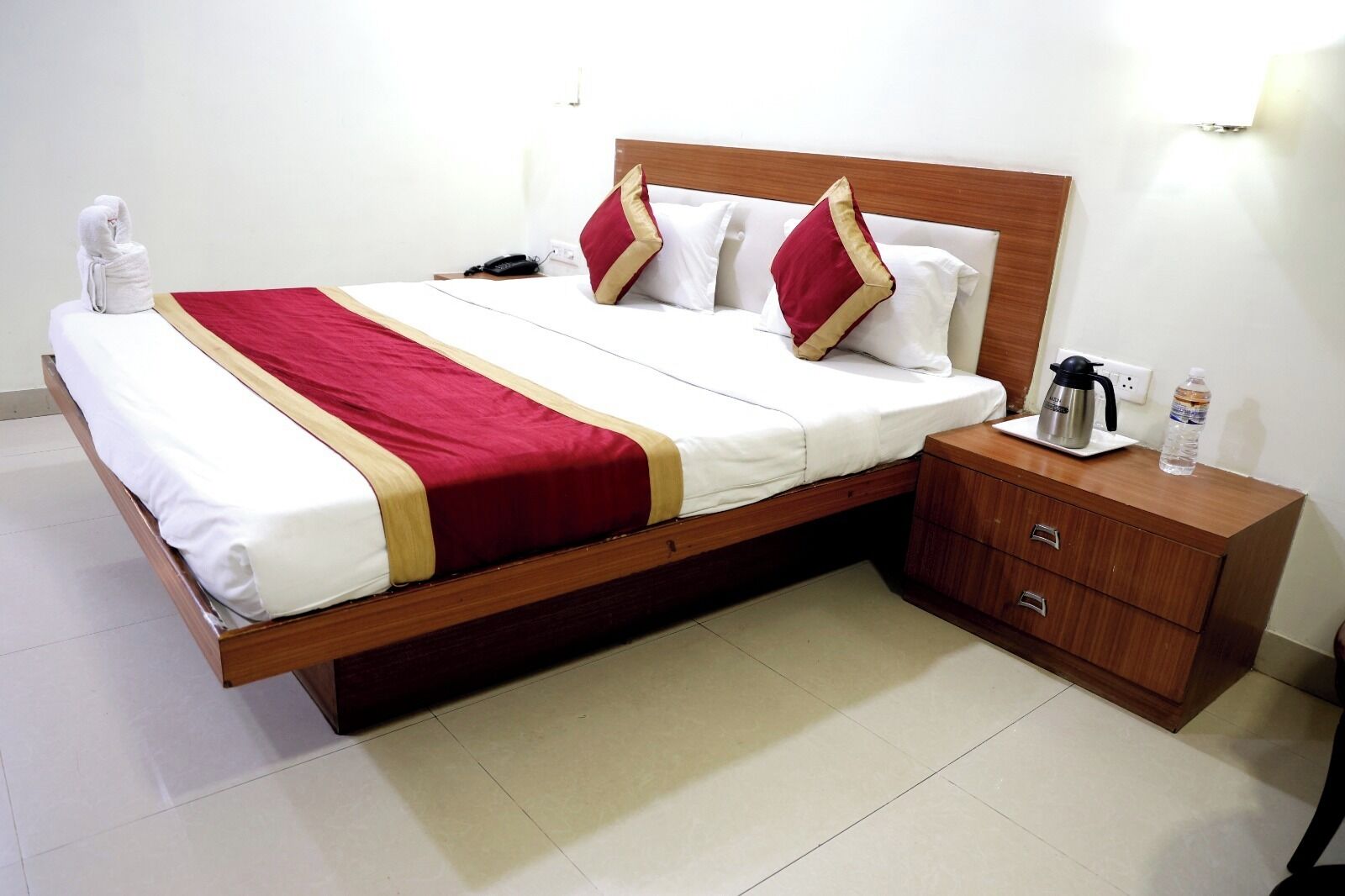 A hotel room with a bed, bedside table, and a nightstand.