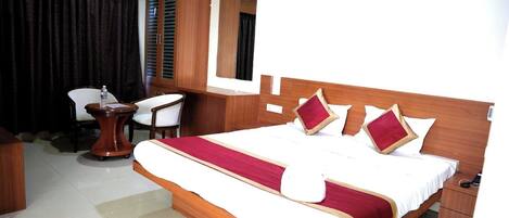 A hotel room with a large bed, a desk, a chair, and a mirror.