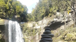 Een stapel gladde stenen in een natuurlijke omgeving, met een waterval op de achtergrond.