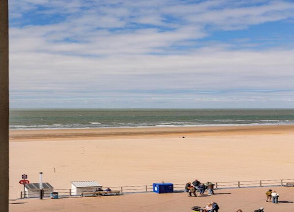 A beach with a sandy shore, a few people, and a clear sky.