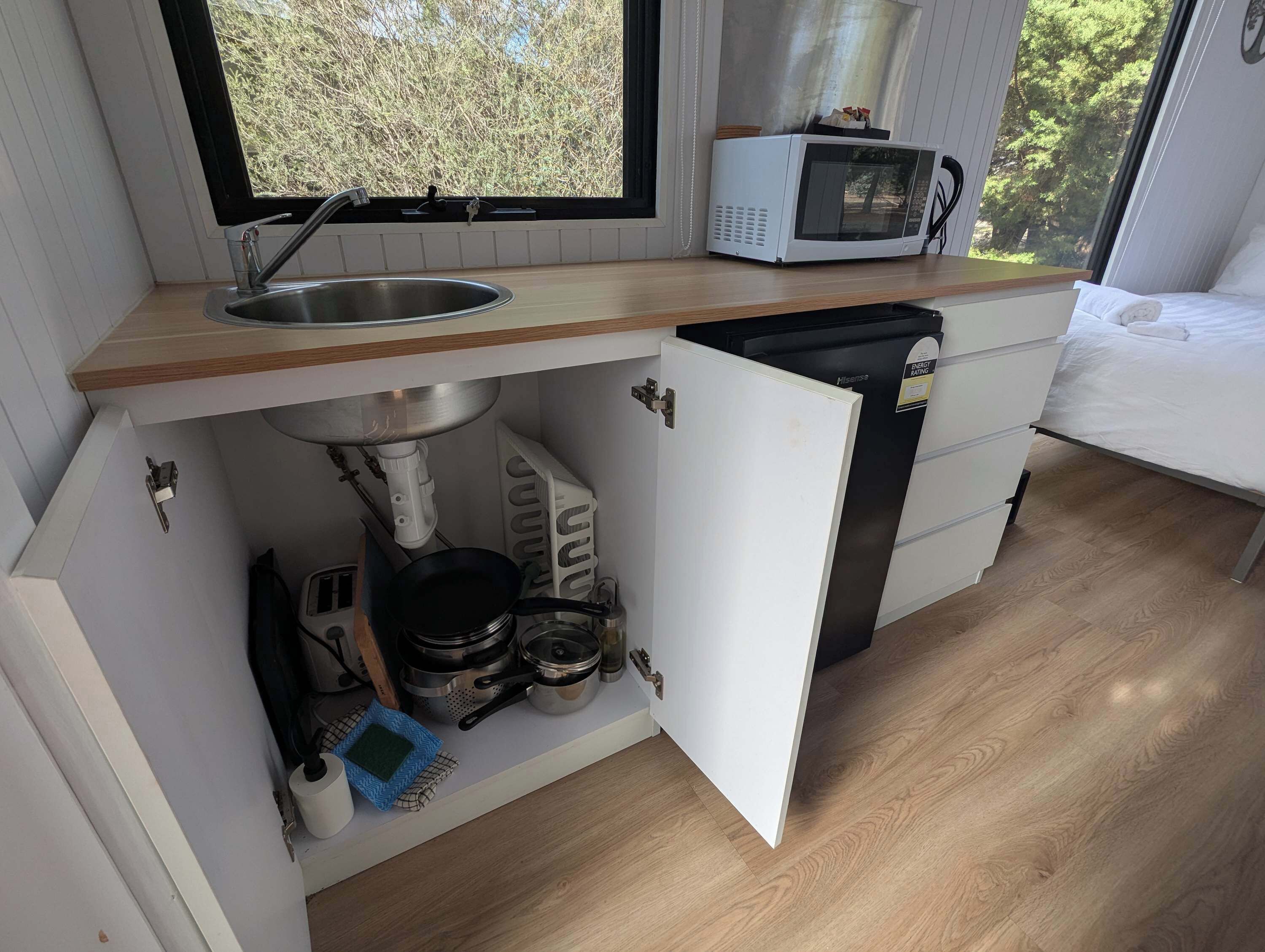 Una kitchenette compacta con pileta, microondas y heladera pequeña.