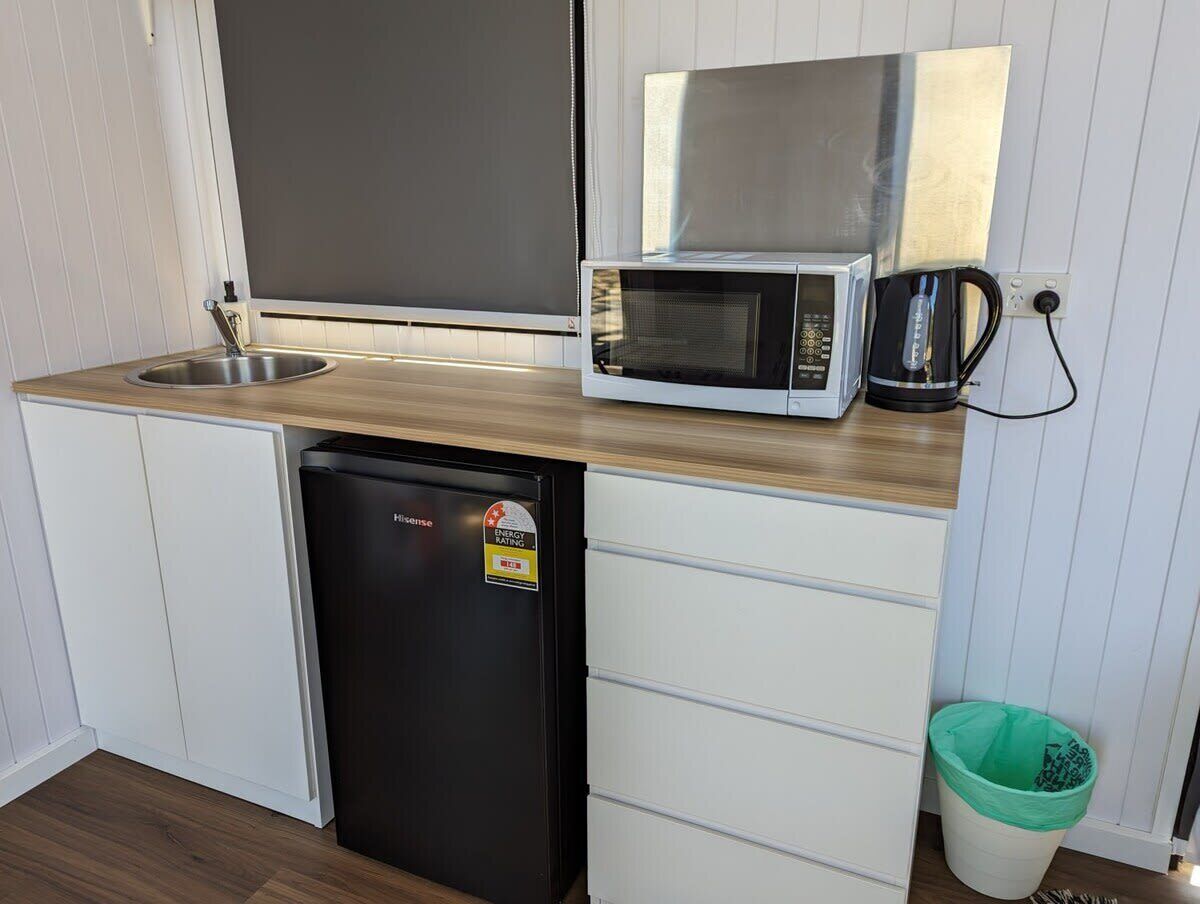 A compact kitchenette with a microwave, sink, and a compact refrigerator.