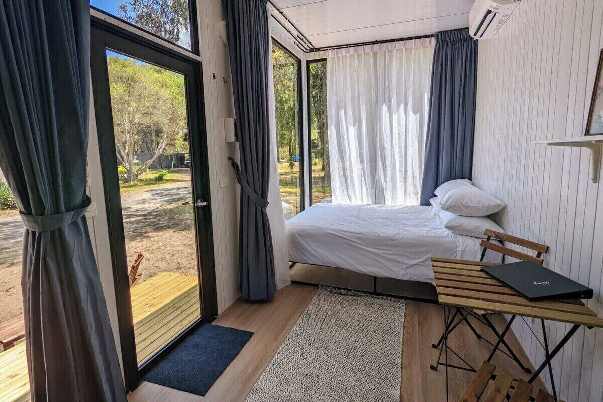 Un dormitorio con cama, escritorio y vistas al exterior.
