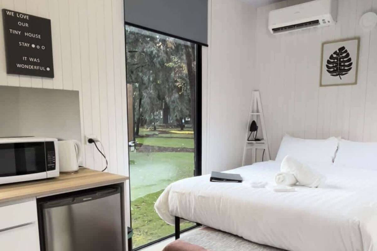 Un dormitorio moderno con cama, mesita de noche y vistas a un parque.