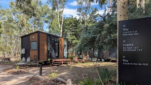 A small cabin with a wooden exterior, a bench, and a sign indicating Tiny cabins and Rose Gap View. - Tiny Away Escape at Grampians Edge (Dadswells Bridge)