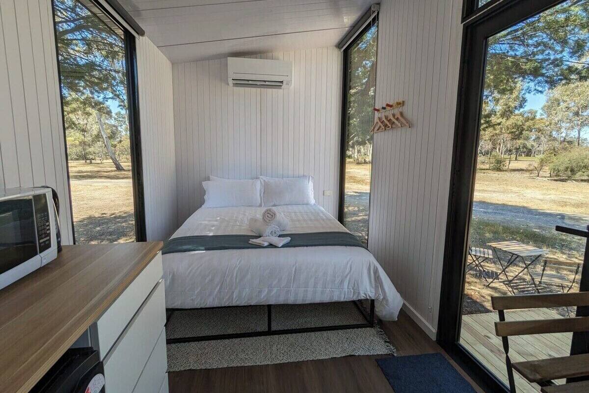 Un dormitorio moderno con una cama, un escritorio pequeño y vistas al exterior.