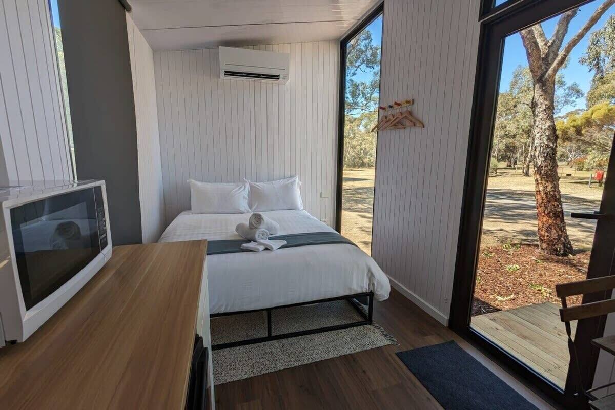 Un dormitorio moderno con cama, televisión y vistas al exterior.
