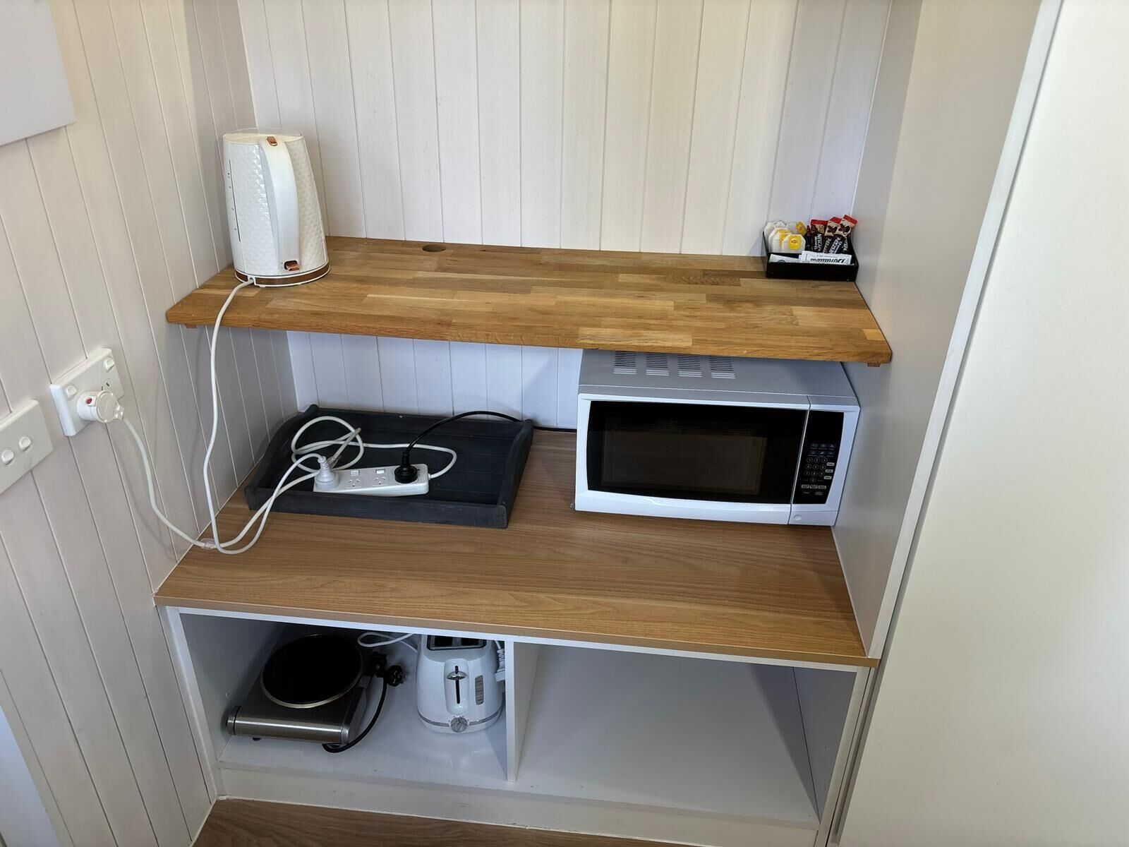 Eine Küche mit Mikrowelle, Toaster und Wasserkocher auf Holzböden.